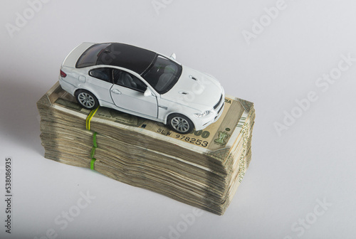 A toy car placed on the heap of Indian rupee bank notes. An idea for 'car loan' or 'Indian automobile market'