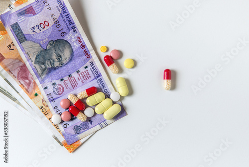 Assorted capsules and tablets placed with Indian rupee currency notes. Concept for cheap generic medicine or expenses for medical treatment.