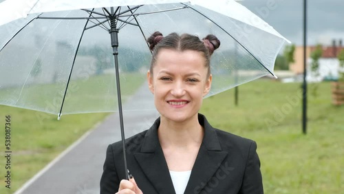 A woman in a black jacket under a transparent umbrella, on the street of the city, outdoors. Rain.