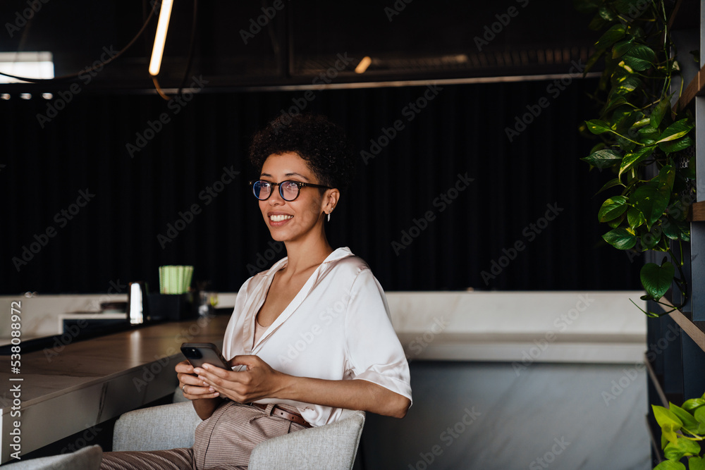 Middle-aged businesswoman using cellphone while sitting at cafe Middle-aged businesswoman using cellphone while sitting at cafe
