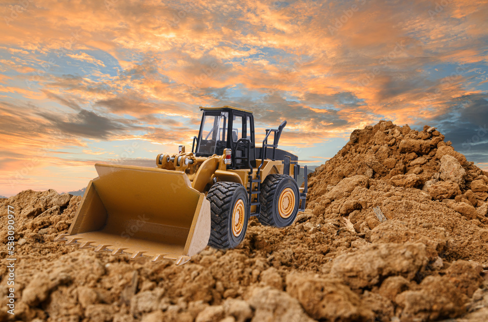 Wheel loader are digging the soil in the construction site on the sunset background . Wheel loader are digging the soil in the construction site on the sunset background .