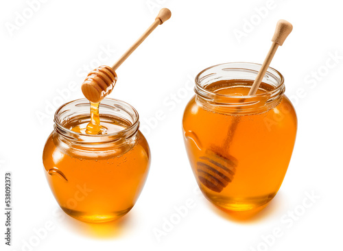 Two glass jars with liquid honey set isolated on white background. Wooden dippers