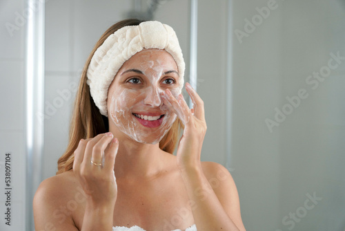 Skincare woman washing face foaming soap scrubbing skin. Face wash exfoliation scrub soap woman washing scrubbing with skincare cleansing product. Enjoying relaxing time. photo