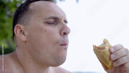 Young handsome man eating empanadas pie on camera, portrait chef with traditional argentinian pie an outdoors. Close up