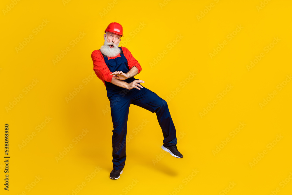 Full body photo of handsome grandpa plumber dancing have fun discount wear blue workwear overall red helmet isolated on yellow background