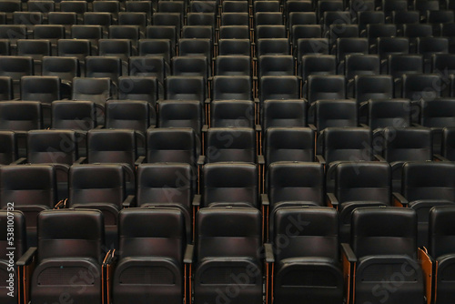 Theater auditorium with emphasis on the black chairs and wooden sides  all the same giving continuity and lines.