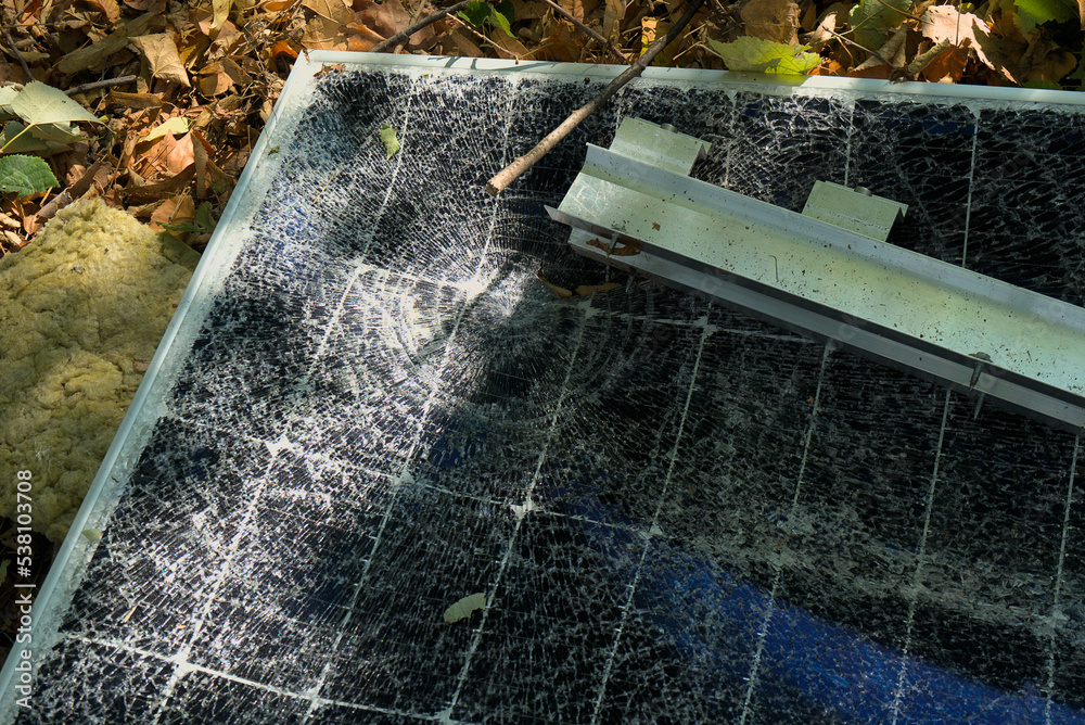 A broken solar panel, a torn panel mount lie on the ground