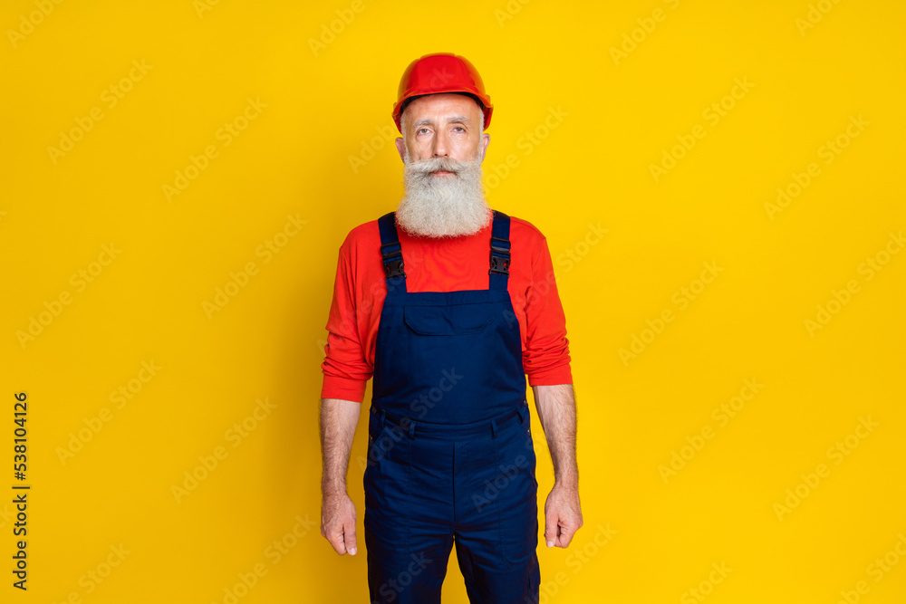 Photo of focused concentrated aged construction worker person isolated on yellow color background Photo of focused concentrated aged construction worker person isolated on yellow color background