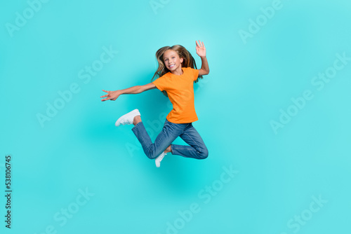 Full body length photo of excited crazy pretty schoolkid girl jumping air trampoline carefree hand acitivity movement isolated on aquamarine color background