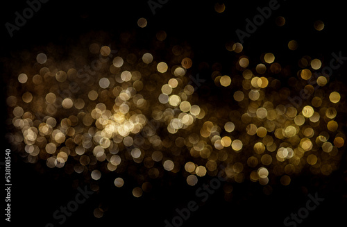 Golden blurred glitter lights at black background.