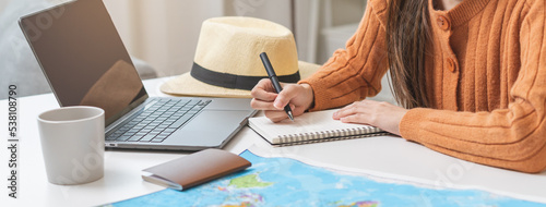 Travel planning, vacation, holiday trip concept, asian young tourist woman hand take note, check list using laptop searching information booking ticket or hotel online, preparation for journey trip. photo