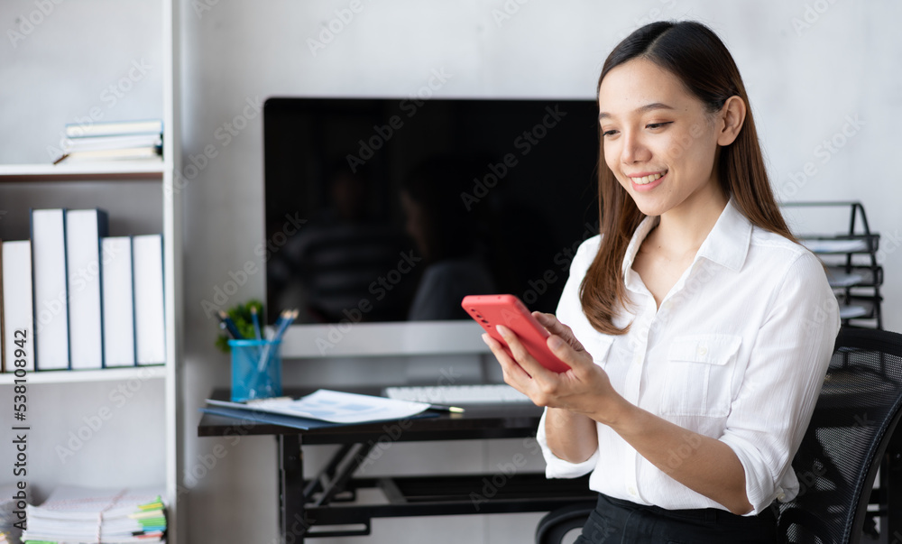 Asian businesswoman in formal suit in office happy and cheerful during using smartphone and working