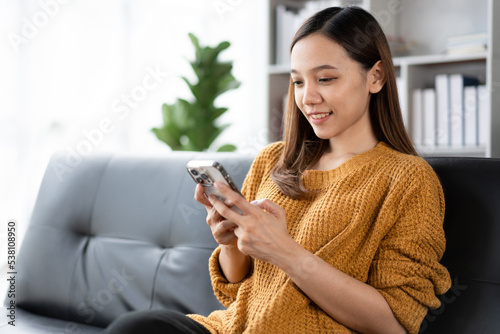 Asian woman using the smartphone on the sofa.