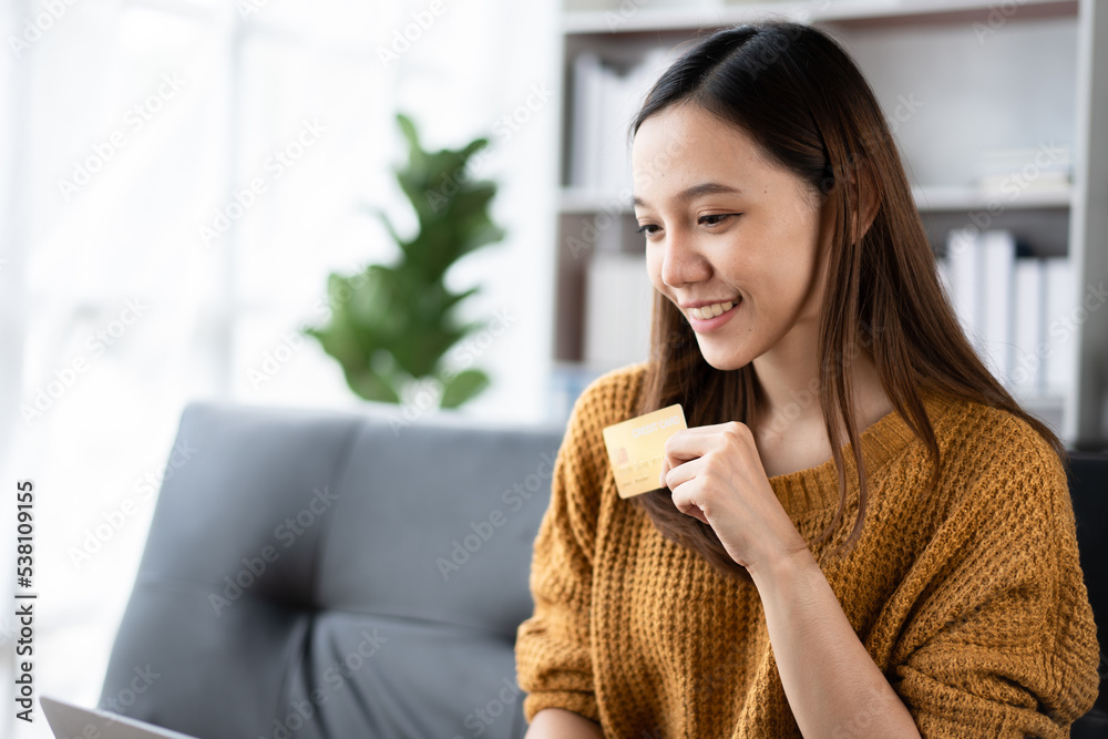 Young Asian woman using credit card and mobile phone for online shopping in coffee shop or coworking space. Young Asian woman using credit card and mobile phone for online shopping in coffee shop or coworking space.