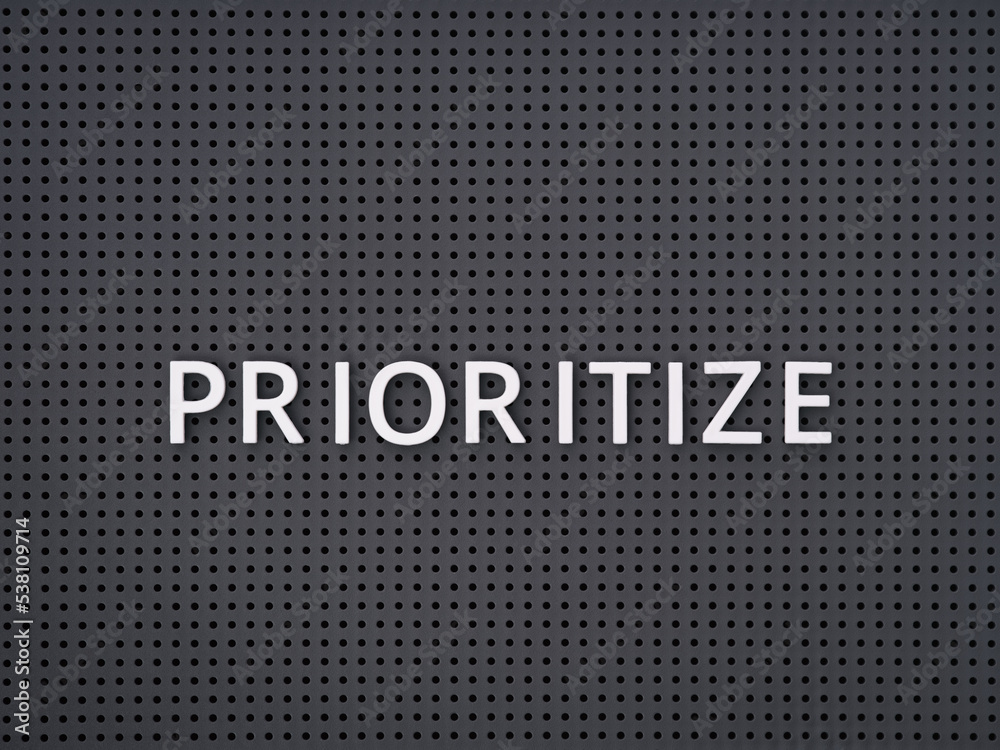 Word Prioritize spelled out with white letters on gray pegboard Word Prioritize spelled out with white letters on gray pegboard
