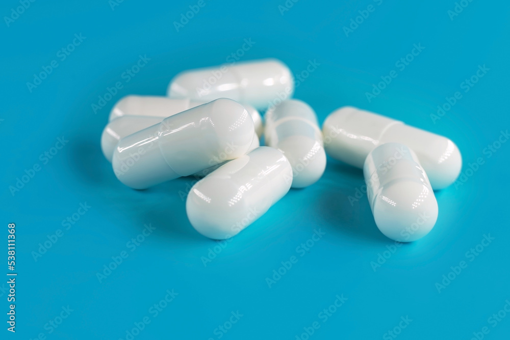 Medical pills or capsules on a blue background close-up. Medical preparations. Health