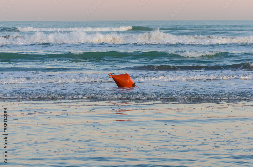 Una boa rossa abbandonata galleggia sulle onde del mare al Lido di Venezia in una giornata invernale Una boa rossa abbandonata galleggia sulle onde del mare al Lido di Venezia in una giornata invernale