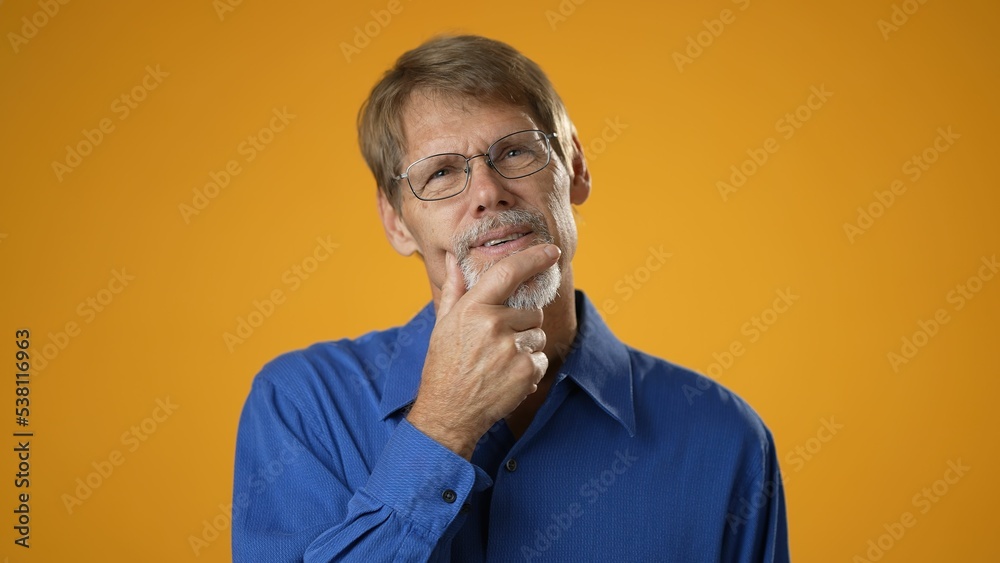 Portrait of thinking pondering mature man in blue shirt having idea moment on solid yellow studio background. Smiling happy guy showing eureka Portrait of thinking pondering mature man in blue shirt having idea moment on solid yellow studio background. Smiling happy guy showing eureka