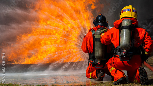 Firefighter on duty firefighting, Asian fireman spraying high pressure water, Fireman in fire fighting equipment uniform spray water from hose for fire fighting. © Darunrat