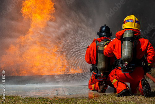 Firefighter on duty firefighting  Asian fireman spraying high pressure water  Fireman in fire fighting equipment uniform spray water from hose for fire fighting.