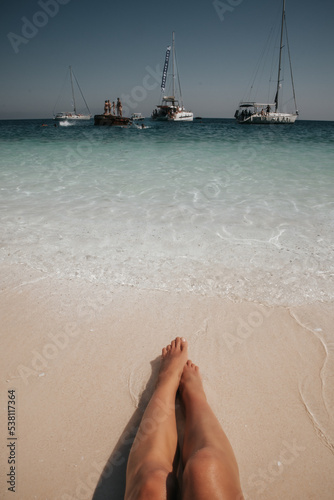 Fototapeta Naklejka Na Ścianę i Meble -  Kobiece nogi na plaży z widokiem na morze
