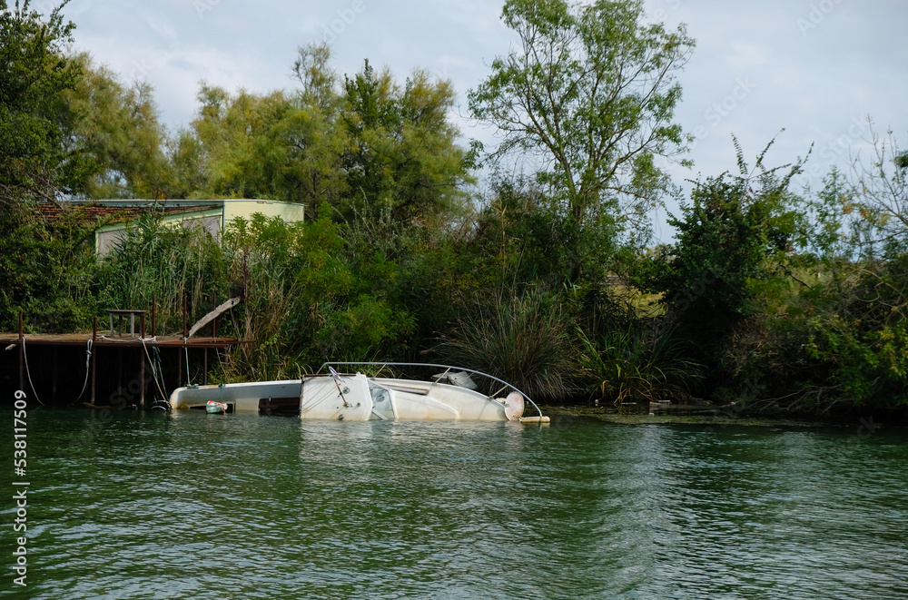 Fototapeta premium An abandoned sunken yacht or boat in the waters of the Delta of the Rhone River, Camargue, France.