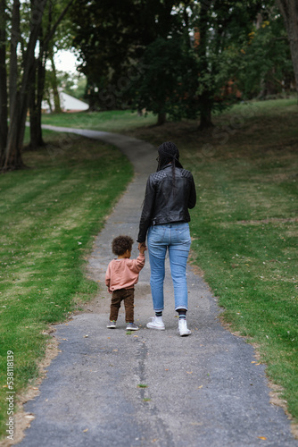 Black mother walking on sidewalk with biracial toddler