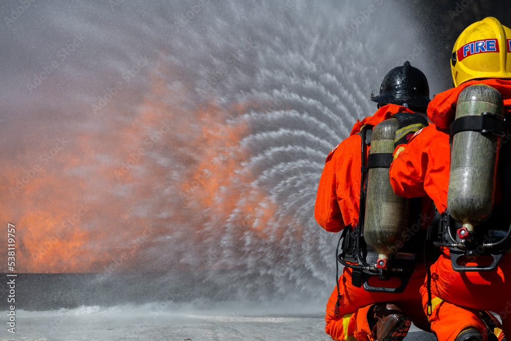 Asian firefighter on duty firefighting, Asian fireman spraying high pressure water, Fireman in fire fighting equipment uniform spray water from hose for fire fighting. Asian firefighter on duty firefighting, Asian fireman spraying high pressure water, Fireman in fire fighting equipment uniform spray water from hose for fire fighting.