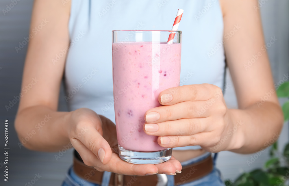 Woman holding glass of tasty raspberry smoothie indoors, closeup Woman holding glass of tasty raspberry smoothie indoors, closeup