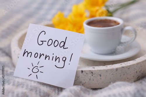 Φωτογραφία Cup of coffee, flowers and card with phrase GOOD MORNING! on knitted paid, close