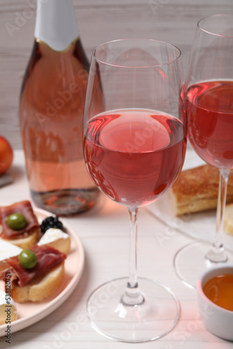 Delicious rose wine and snacks on white wooden table