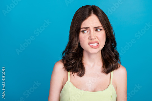 Photo of arrogant moody girl dressed green clothes biting lip looking empty space isolated blue color background