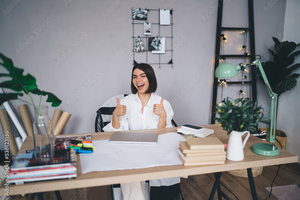 Cheerful female showing like gesture while working in creative office Cheerful female showing like gesture while working in creative office