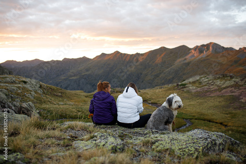 Women with dog sitting on rock in mountains photo