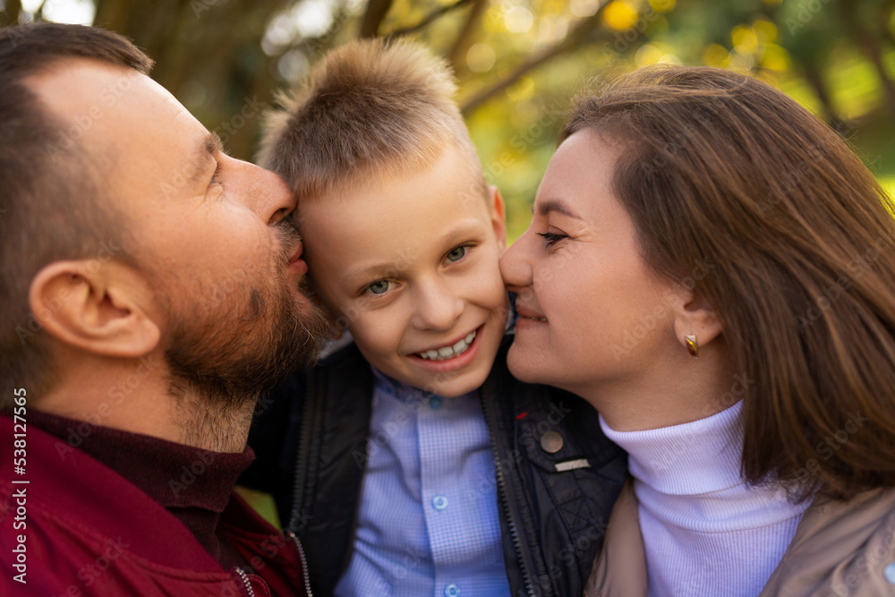 mom and dad kissing a child boy between themselves, close-up portrait mom and dad kissing a child boy between themselves, close-up portrait