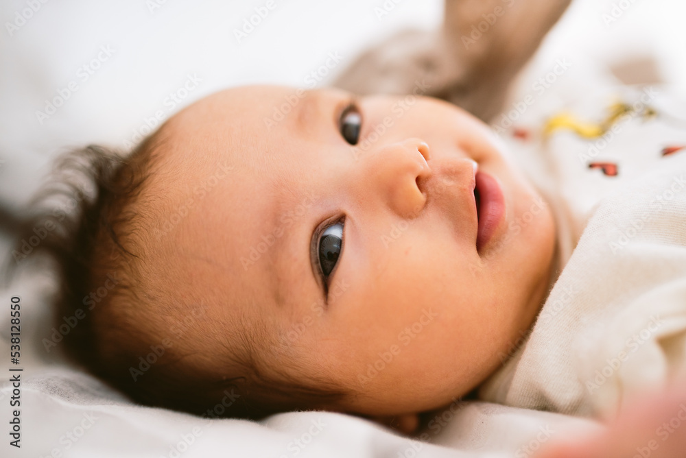close up of cute smiling latino baby girl in bed with morning light. Waking up in bed. healthy hispanic baby with warm natural light