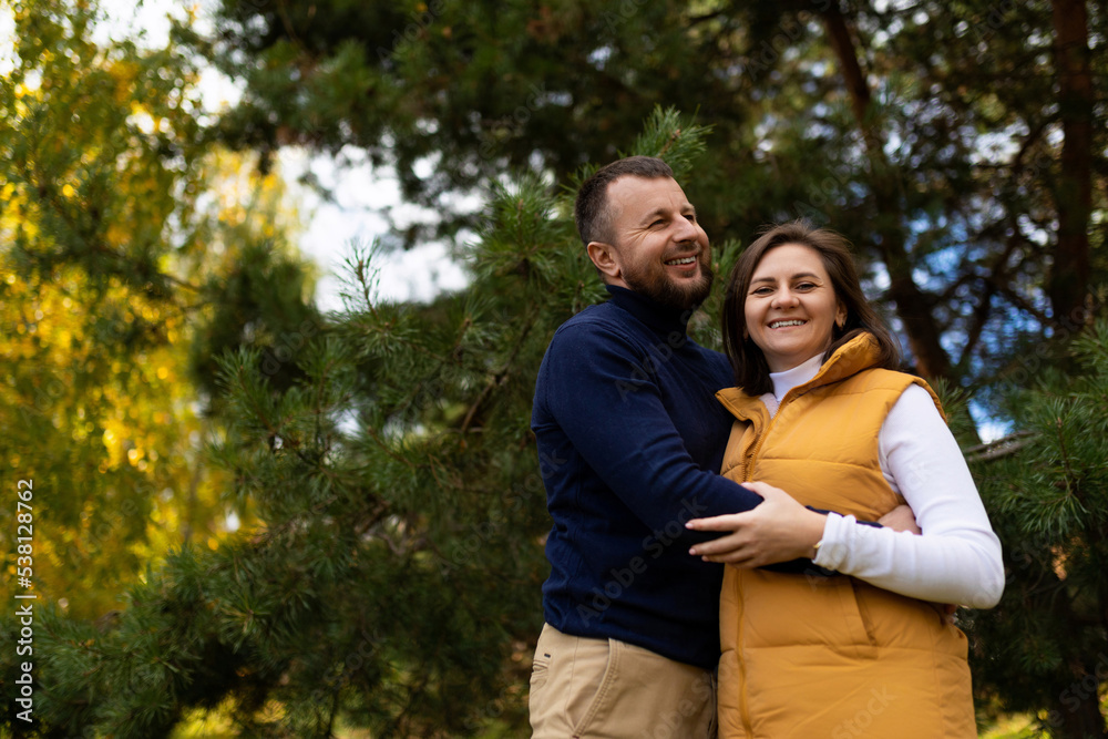 a happy husband joyfully hugs his wife against the backdrop of an autumn forest a happy husband joyfully hugs his wife against the backdrop of an autumn forest