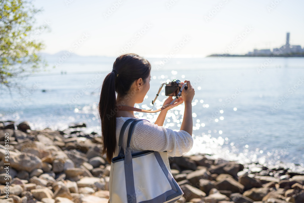 Woman visit the sea beach and use digital camera to take photo
