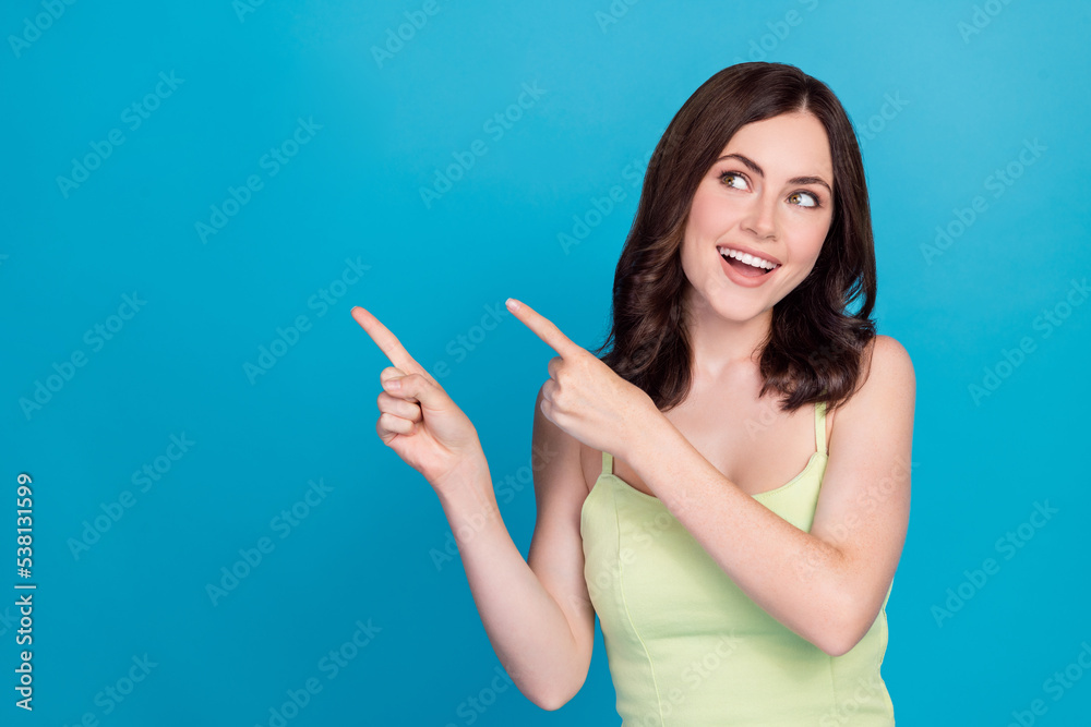 Photo of dreamy adorable lady wear green singlet looking pointing empty space isolated blue color background Photo of dreamy adorable lady wear green singlet looking pointing empty space isolated blue color background