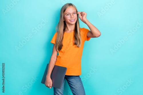 Photo of small cute schoolgirl kid positive smiling hold laptop touch new eyeglasses smart learner distance education isolated on aquamarine color background