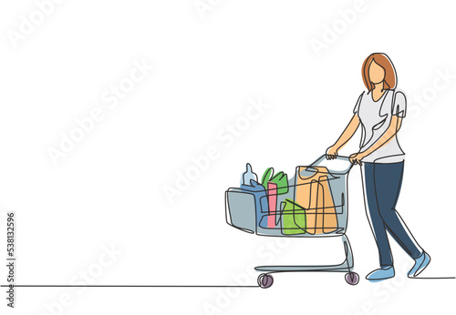 One continuous line drawing young happy female pushing trolley at supermarket while shopping fruits, vegetables, breads, milk. Shopping in hypermarket concept. Single line draw design illustration