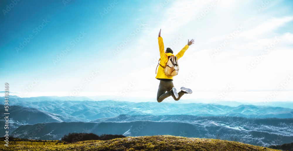 Happy man with open arms jumping on the top of mountain - Hiker with backpack celebrating success outdoor - People, success and sport concept - obrazy, fototapety, plakaty 