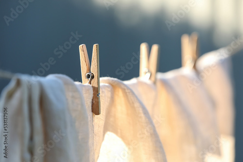 Washing line with drying shirt against blurred background, focus on clothespin photo
