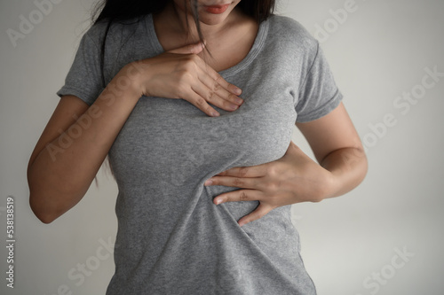 Young Asian woman pressing touching her chest for checking lady breast cancer symptom diagnosis breast self exam(BSE). Woman health inspect cancer awareness concept.	 photo
