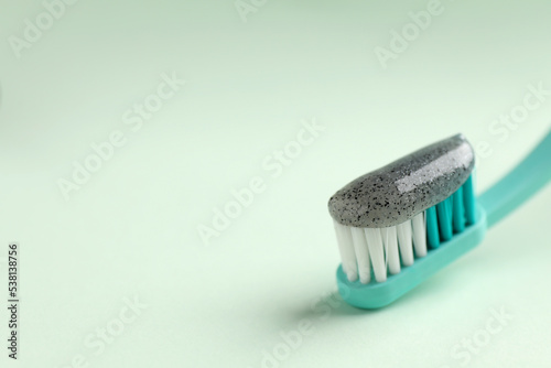 Brush with charcoal toothpaste on white background  closeup. Space for text