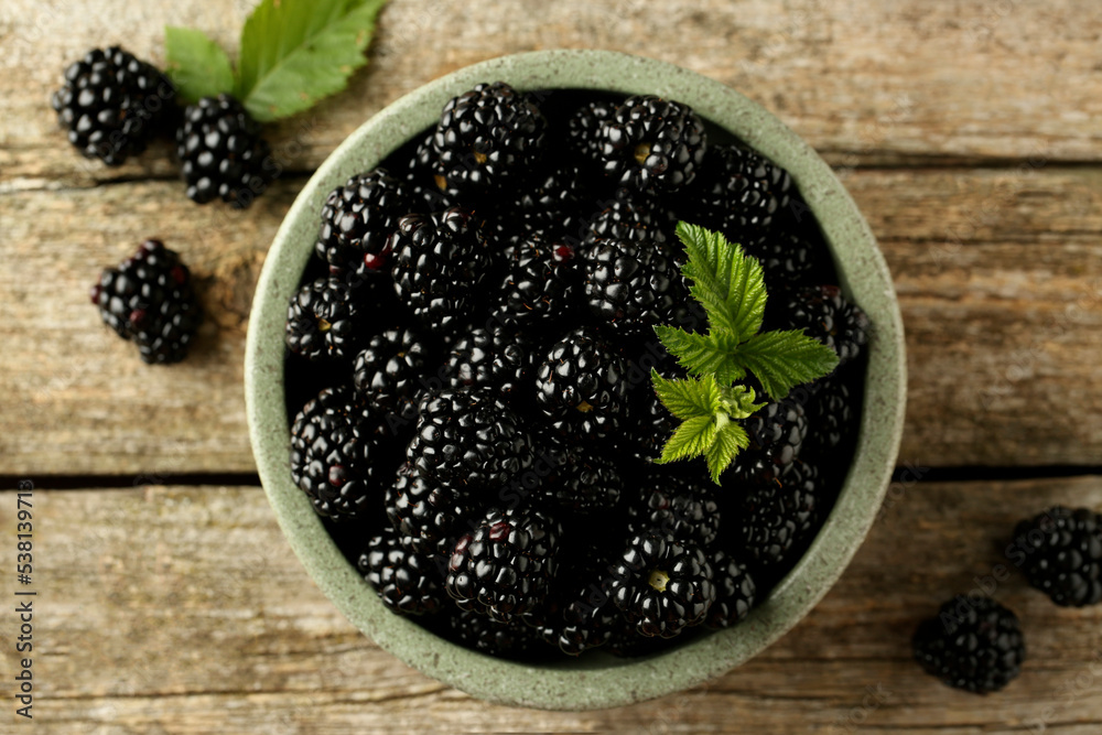 Bowl and fresh ripe blackberries on wooden table, flat lay Bowl and fresh ripe blackberries on wooden table, flat lay