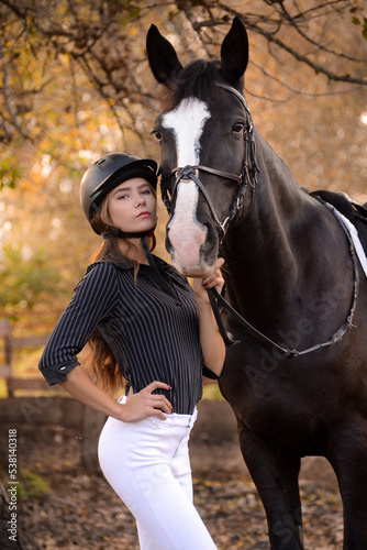 The girl proudly stands next to the horse.