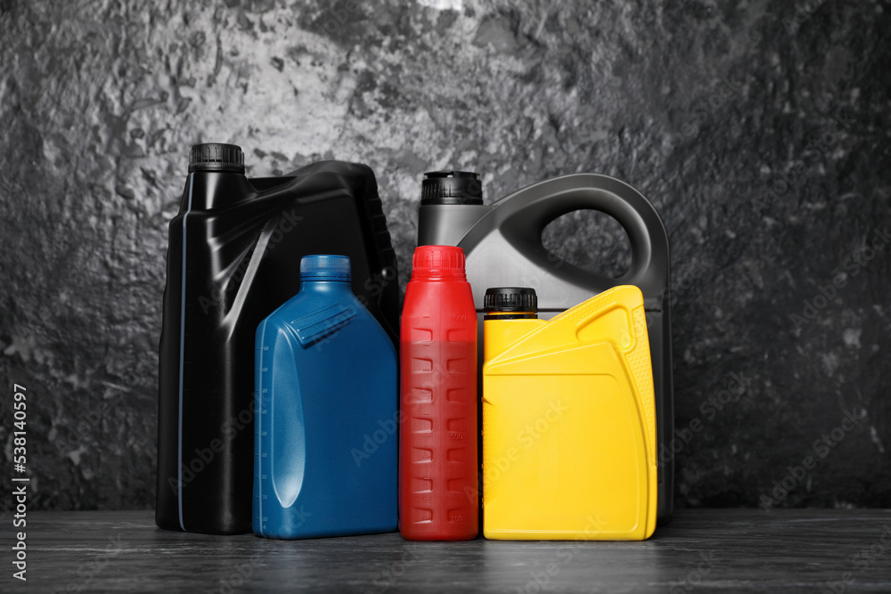 Motor oil in different canisters on black table near dark wall Motor oil in different canisters on black table near dark wall