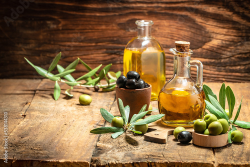 Olive oil in bottles with black and green olives and leaves. extra virgin olive oil jars on a wooden background. place for text