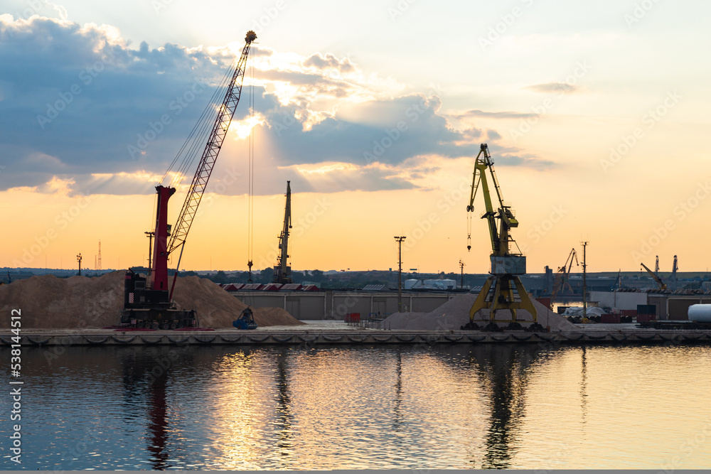 Port cranes on the territory of the seaport in Constanta, Romania, at sunset. Seaport area with cranes.